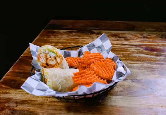 A photo of a wrap and waffle fries.